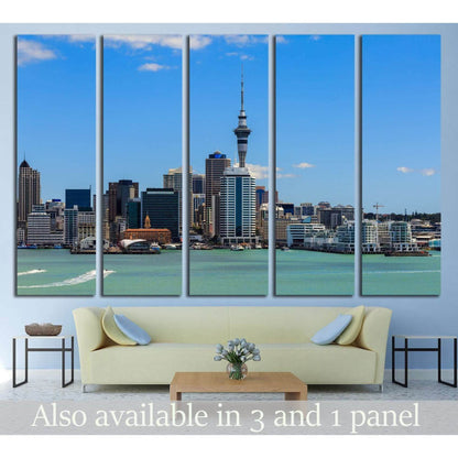 Auckland skyline canvas print with Sky Tower, turquoise harbor, and blue sky above a sofa