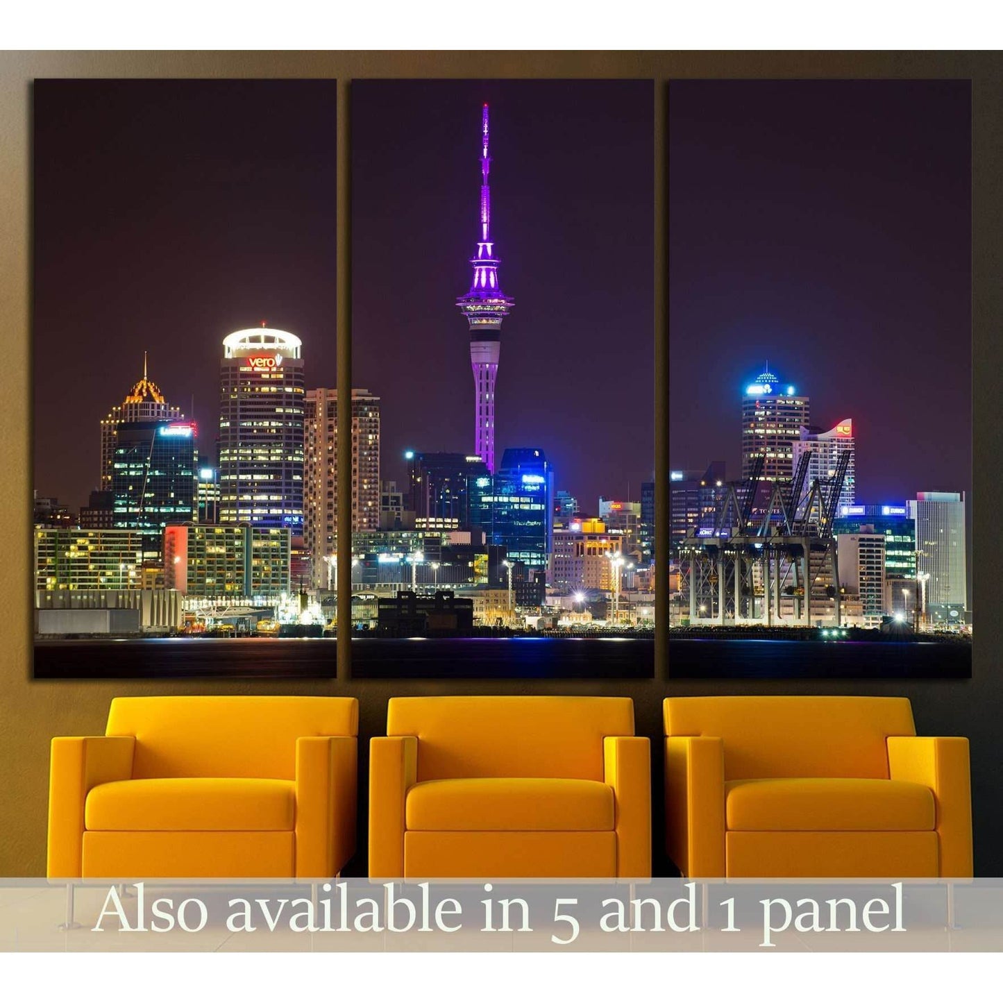 Auckland skyline triptych canvas print with Sky Tower lit purple at night, displayed above yellow chairs