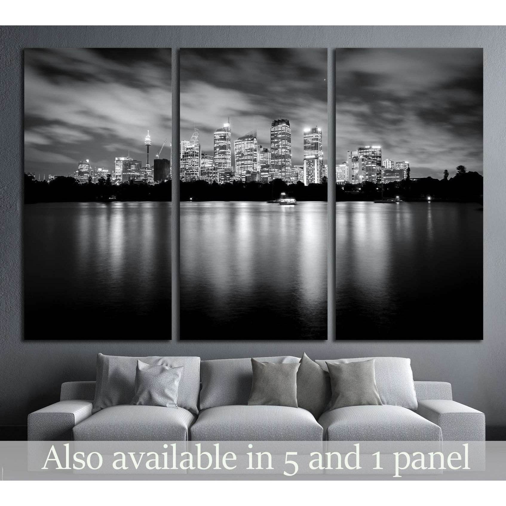Black and white Sydney skyline triptych canvas print above a sofa with night reflections on the water