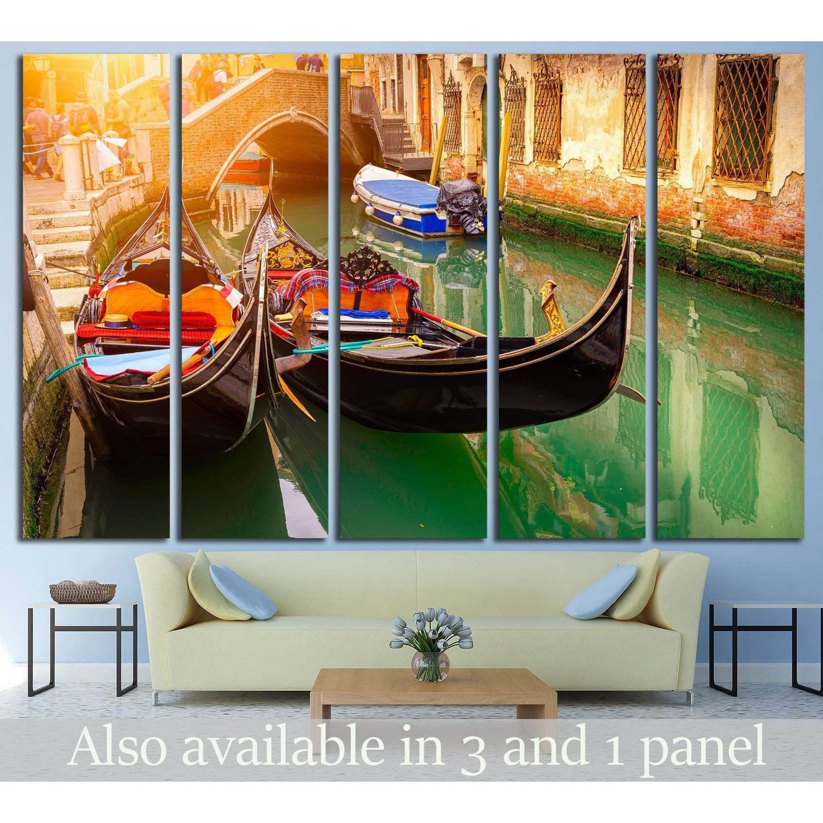 Venice gondola canvas print with two gondolas in green canal water beneath a brick bridge, hung above a sofa