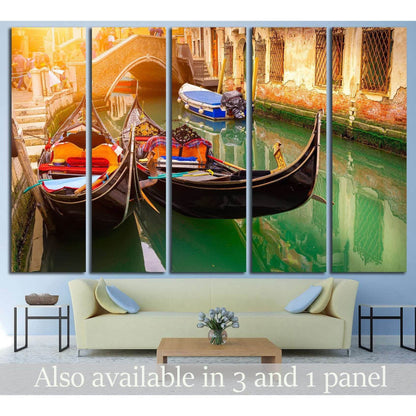 Venice gondola canvas print with two gondolas in green canal water beneath a brick bridge, hung above a sofa