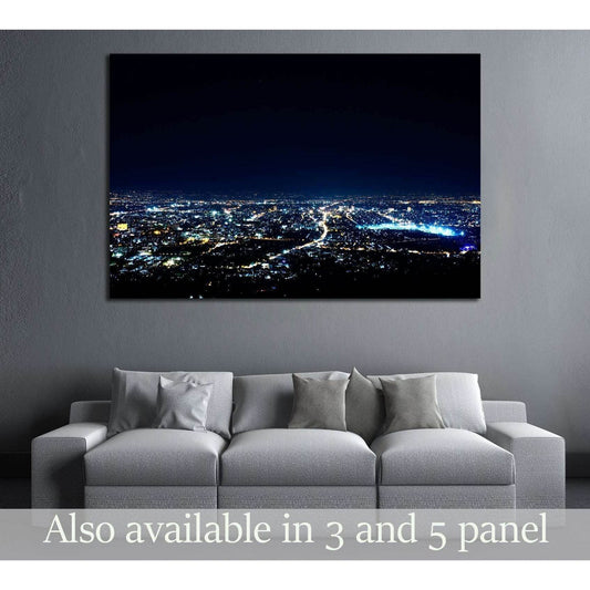 Panoramic city night skyline canvas print with blue lights above a sofa in a modern living room