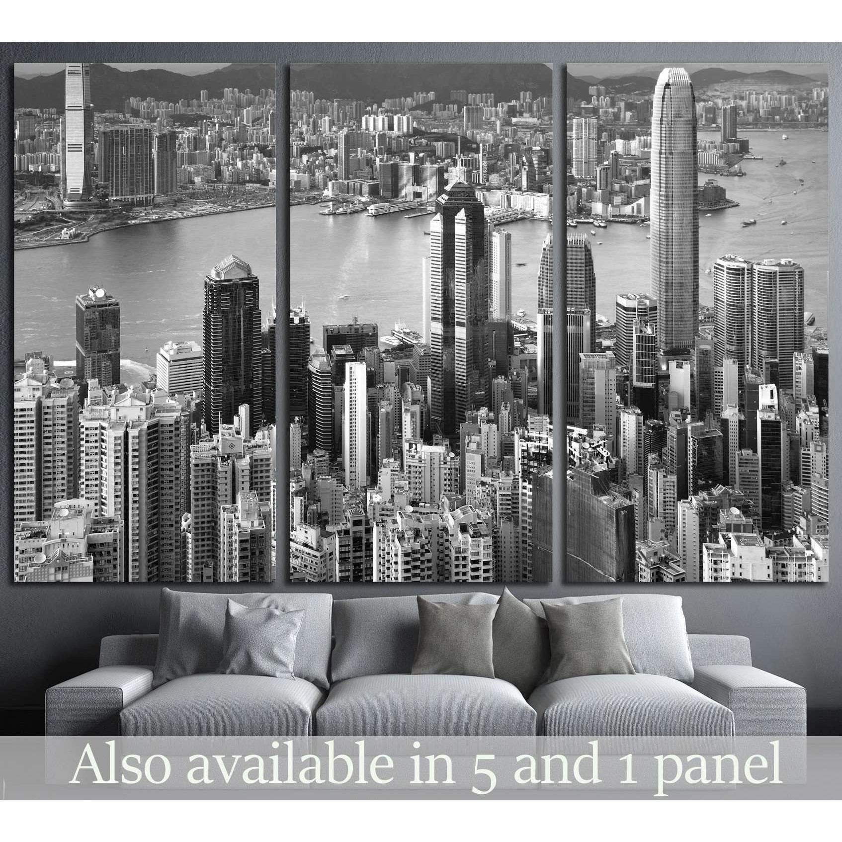 Black and white Hong Kong skyline canvas print in triptych layout above a grey sofa