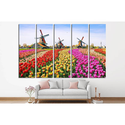 Zaanse Schans Windmills and Tulip Fields Canvas for Vibrant DecorThis canvas print vividly portrays the charming Zaanse Schans with its iconic windmills standing tall above a vibrant field of tulips in the Netherlands. The array of colors and the historic