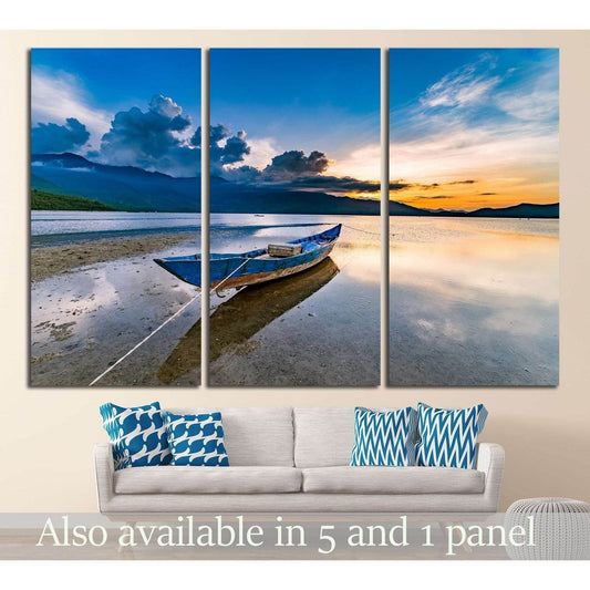 Triptych Lap An Lagoon canvas print with blue boat at sunset above sofa in a modern living room