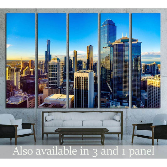 Melbourne skyline canvas print with glass skyscrapers at sunrise above a sofa in a modern living room