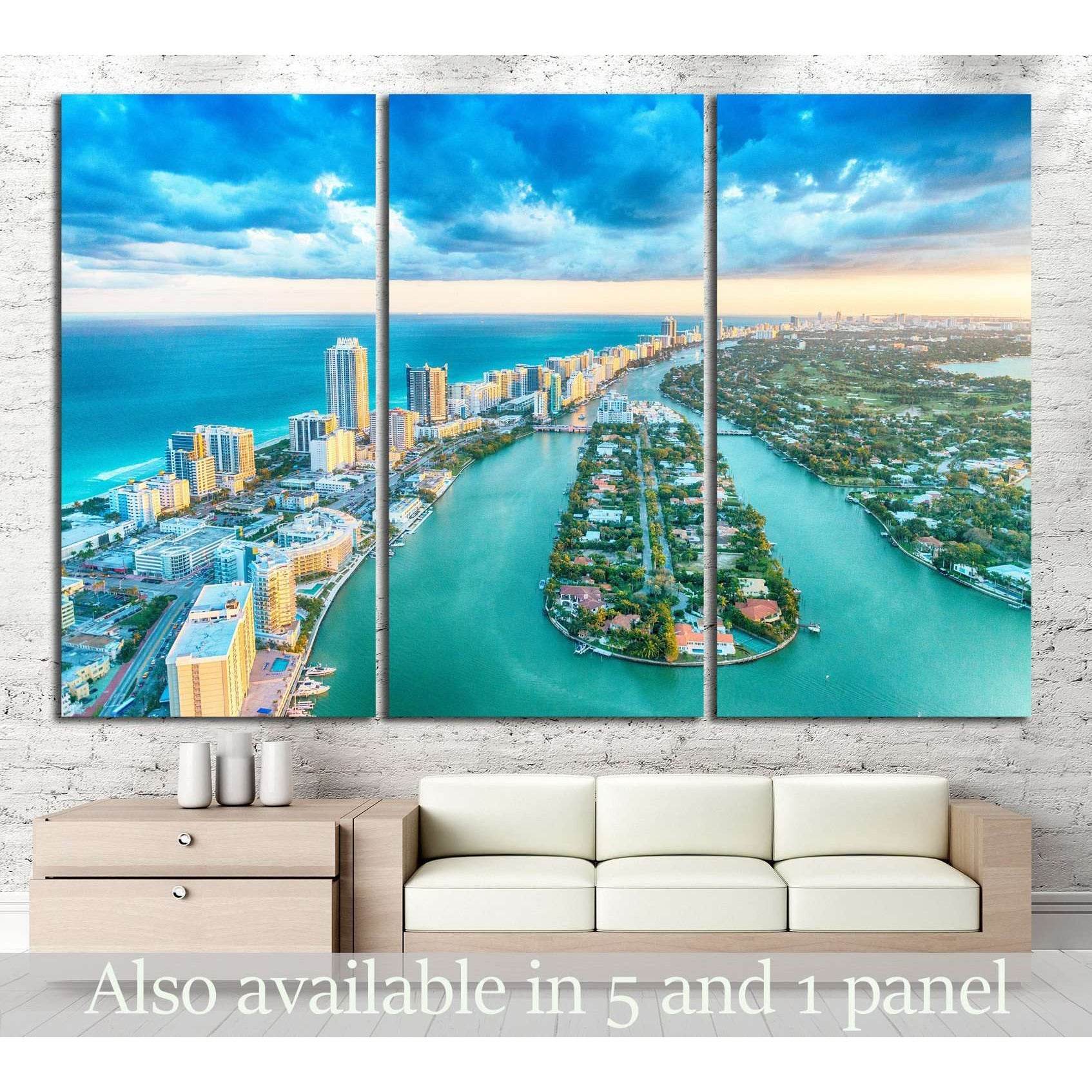 Panoramic Miami Beach aerial canvas print in triptych panels above a sofa in a coastal living room