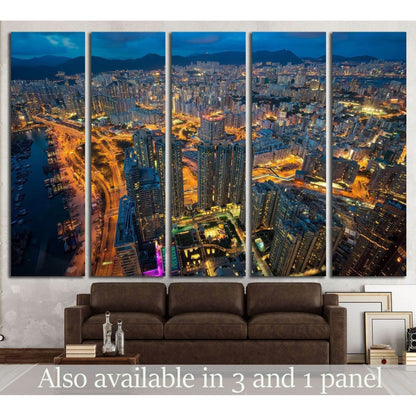 Aerial night city canvas print in five panels above a sofa with glowing roads and blue dusk skyline