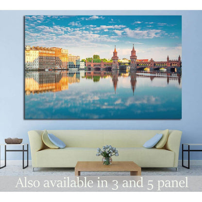 Oberbaum Bridge Berlin canvas print with warm riverside buildings reflected in calm water above a sofa