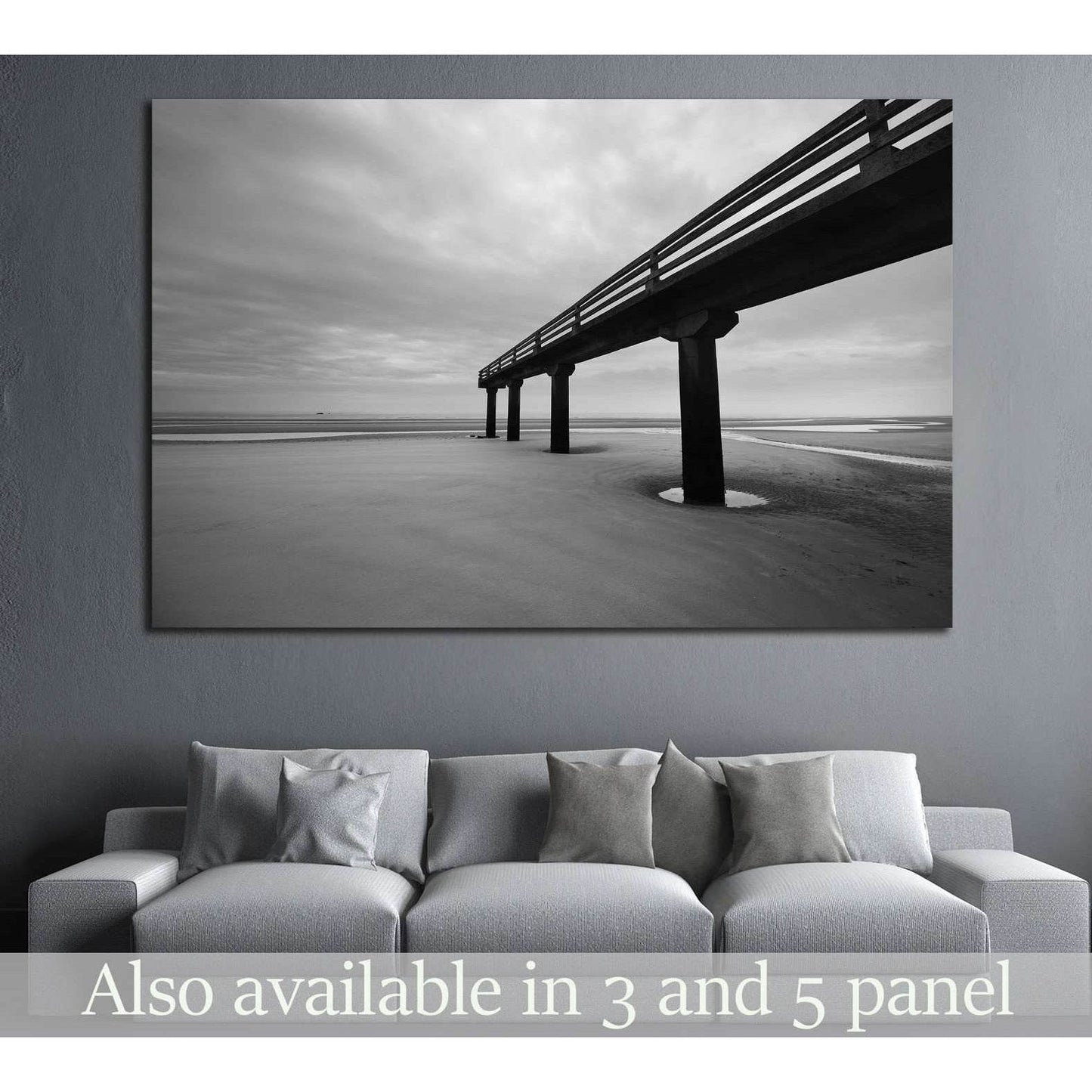 Black and white Omaha Beach pier canvas print hung above a sofa in a modern gray living room