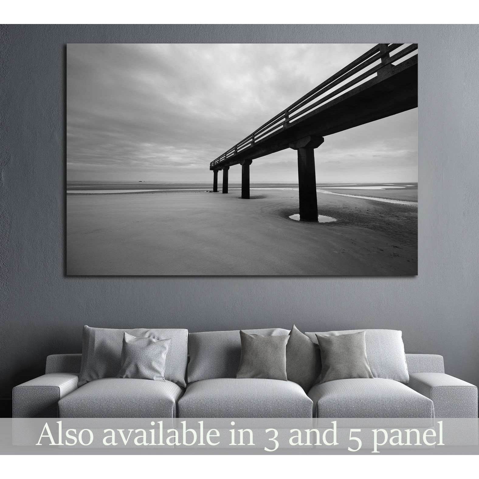 Black and white Omaha Beach pier canvas print hung above a sofa in a modern gray living room