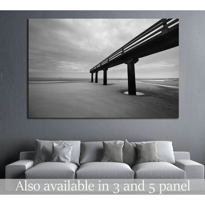 Black and white Omaha Beach pier canvas print hung above a sofa in a modern gray living room