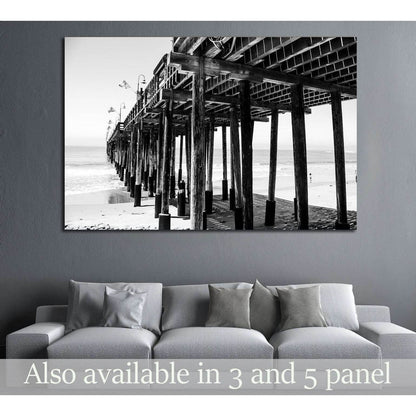 Black and white pier canvas print above a sofa in a modern coastal living room