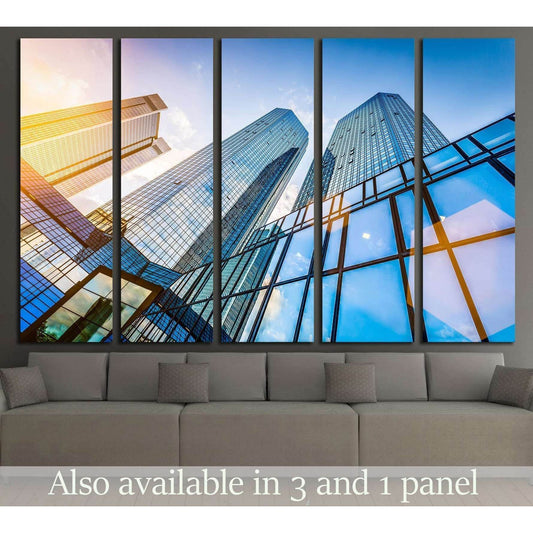 Modern skyscraper canvas print with blue glass towers and golden light, displayed above a sofa