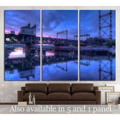 Rusty train bridge over harbor at blue and pink sunset triptych canvas print above brown sofa
