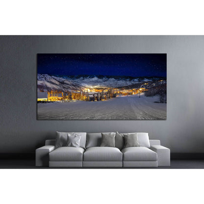 Starlit Ski Village Canvas Print for Cozy Winter DecorThis canvas print features a night-time view of a snow-covered ski village, with glowing lights that offer a warm contrast to the cool blue hues of the evening. The clear starry sky adds a touch of mag