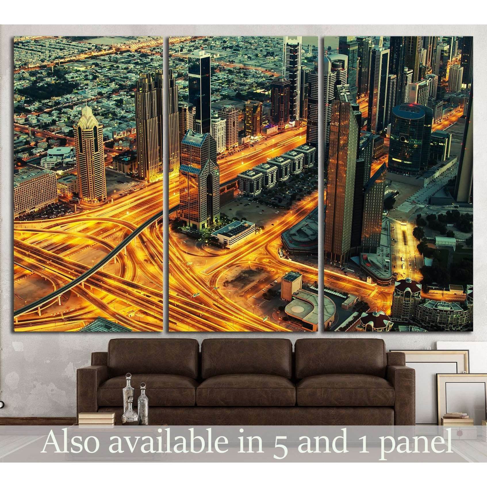 Dubai night skyline canvas print above sofa with glowing highway interchanges and skyscrapers