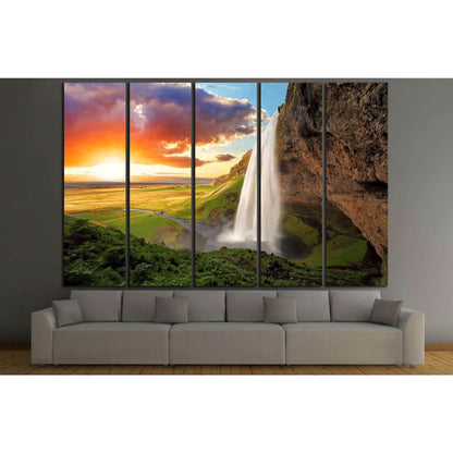 Seljalandsfoss Waterfall Sunset Canvas Print - Majestic Iceland Wall ArtThis canvas print stunningly captures the majestic Seljalandsfoss waterfall in Iceland, set against a striking sunset that bathes the landscape in warm, golden light. The powerful cas